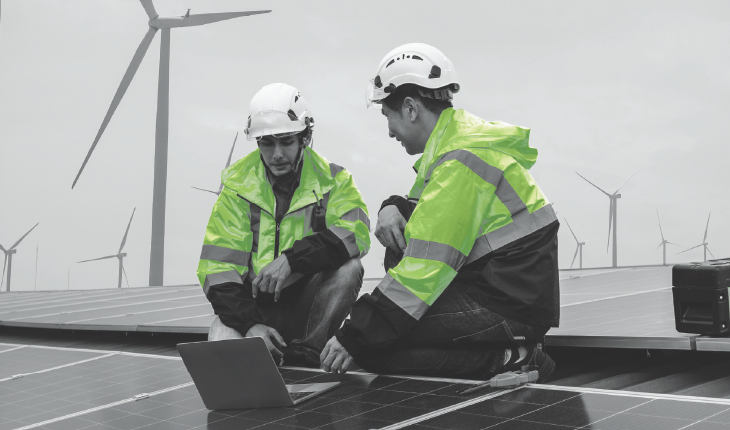 Engineers in front of a Solar and Wind farm